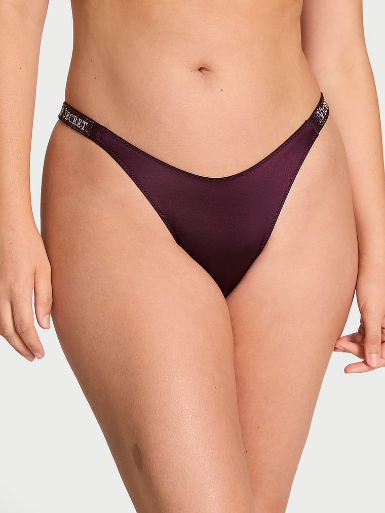 Tanga s lesklými ramínky Shine Strap. Produkt je fialové barvy a pochází z kolekce Very Sexy.